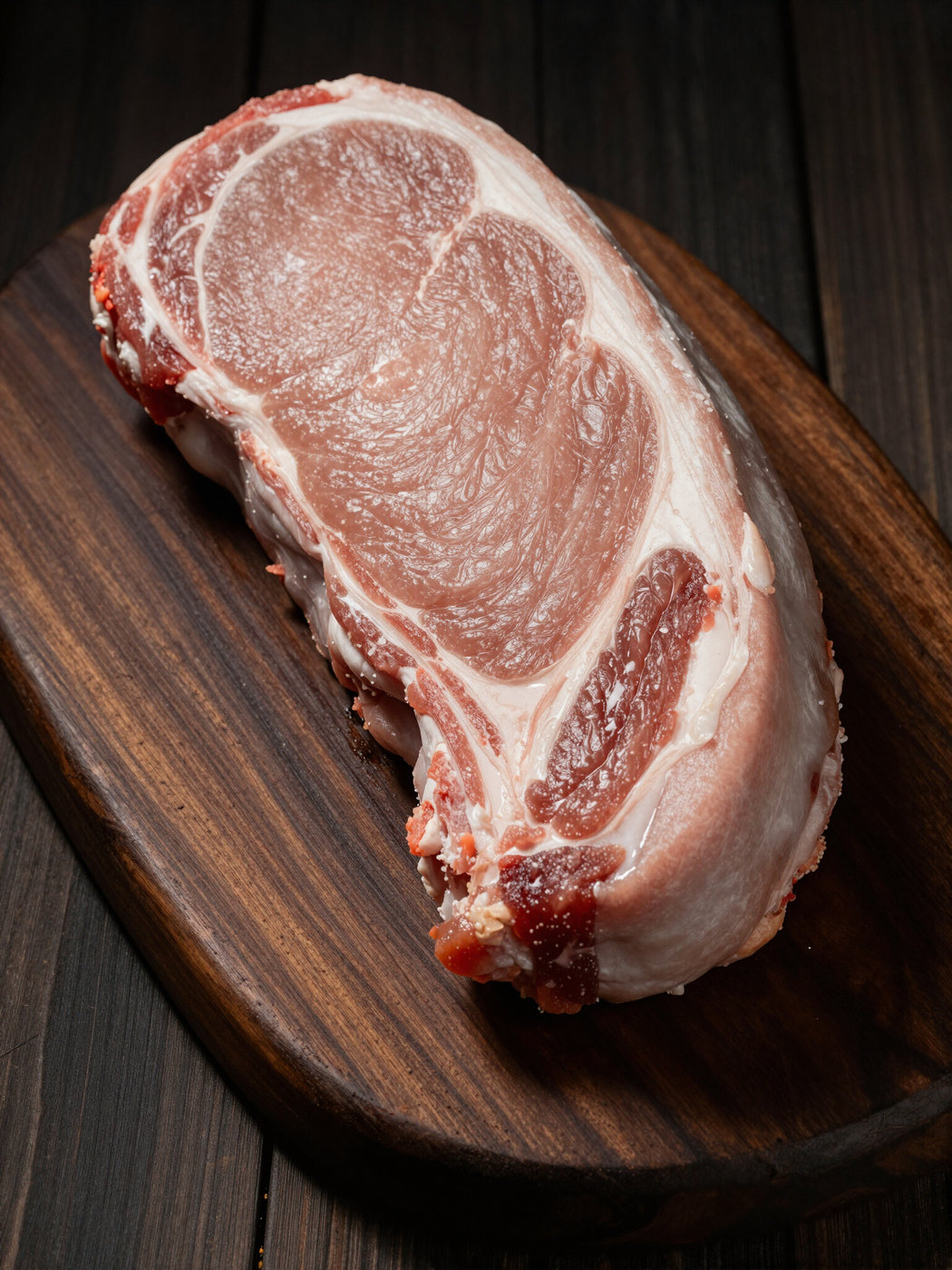 A thick-cut pork chop on a wooden board